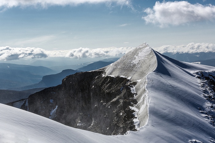 Snowy mountain peak with clouds and valleys
