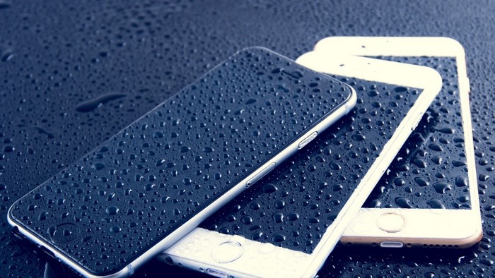 Three iPhones covered in water droplets