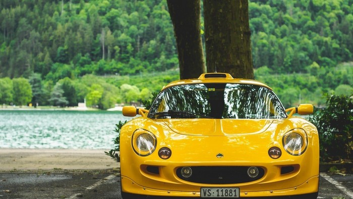 Yellow Lotus Exige parked by a lake