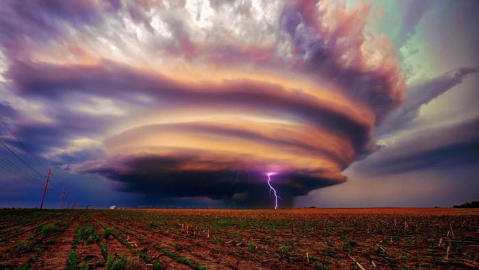 Lightning strikes a supercell thunderstorm over a field