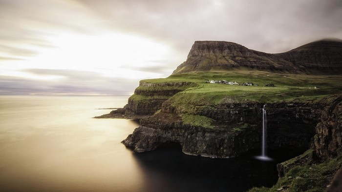 Waterfall cascading from cliffs near village on Faroe Islands