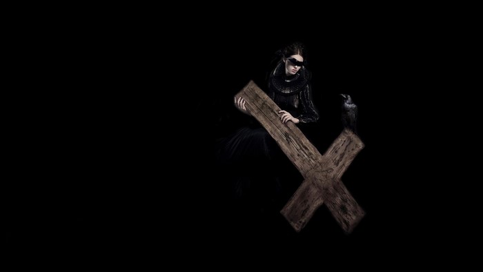 Woman in black with blindfold holding wooden cross and raven