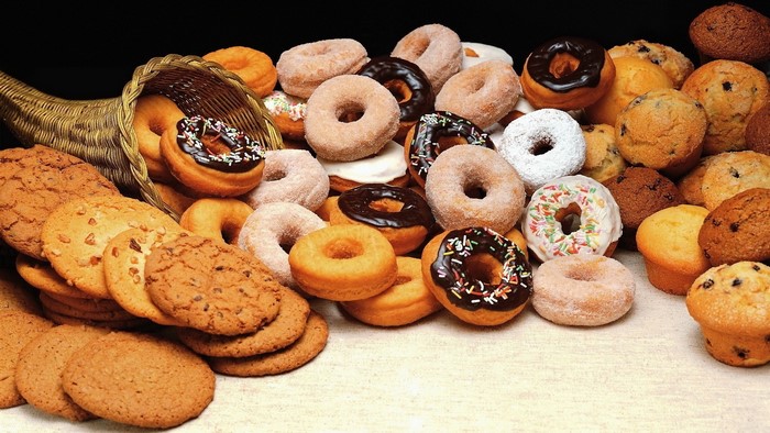 Assortment of donuts, muffins, and cookies spilling from a cornucopia