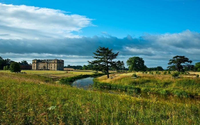 Country house with a river and trees under a cloudy sky