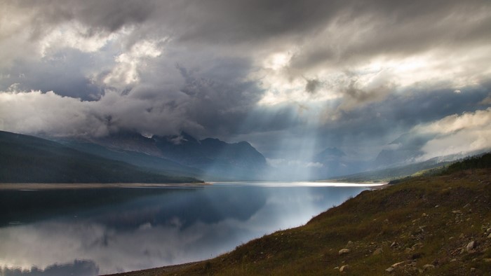 Sunbeams through clouds over a mountain lake