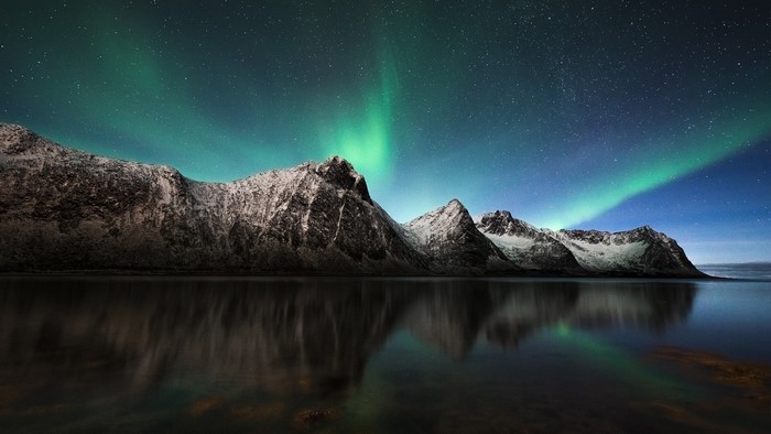 Aurora Borealis over snow-capped mountains in Iceland