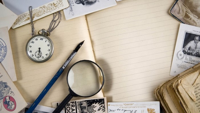 Vintage pocket watch, fountain pen, and magnifying glass on notebook