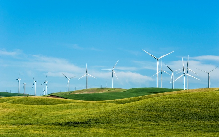 Wind turbines on rolling green hills under a blue sky