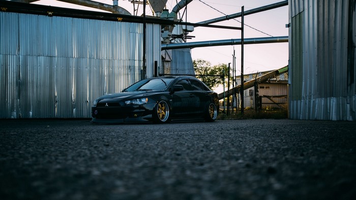 Black Mitsubishi Lancer parked near industrial buildings
