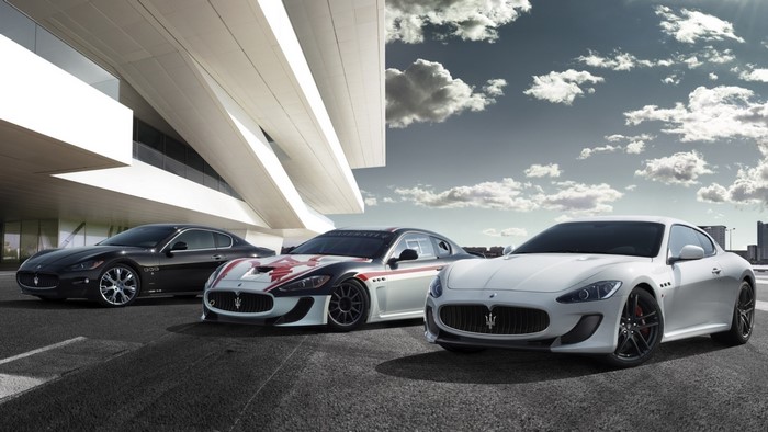 Three Maserati cars parked in front of a modern building