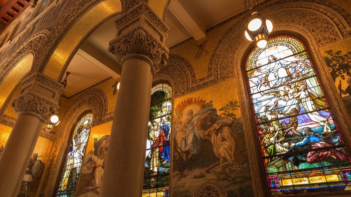 Interior of a cathedral with stained glass windows and mosaics