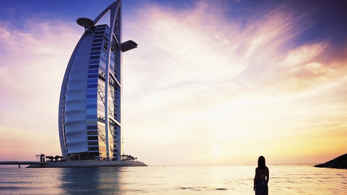 Burj Al Arab Dubai at sunset with a woman on the beach