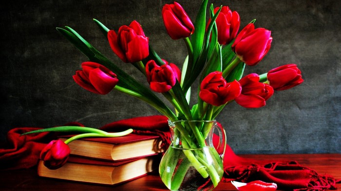 Red tulips in a glass vase with books