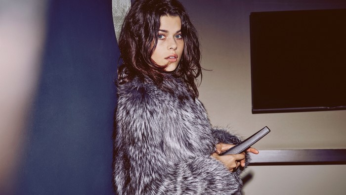 Georgia Fowler in a fur coat holding a remote