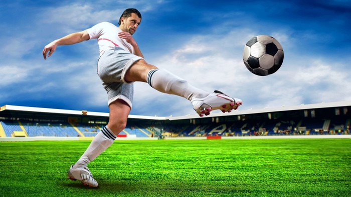 Soccer player kicking a ball on a stadium field