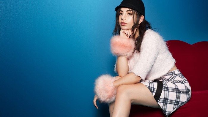 Charli XCX sitting on a red couch