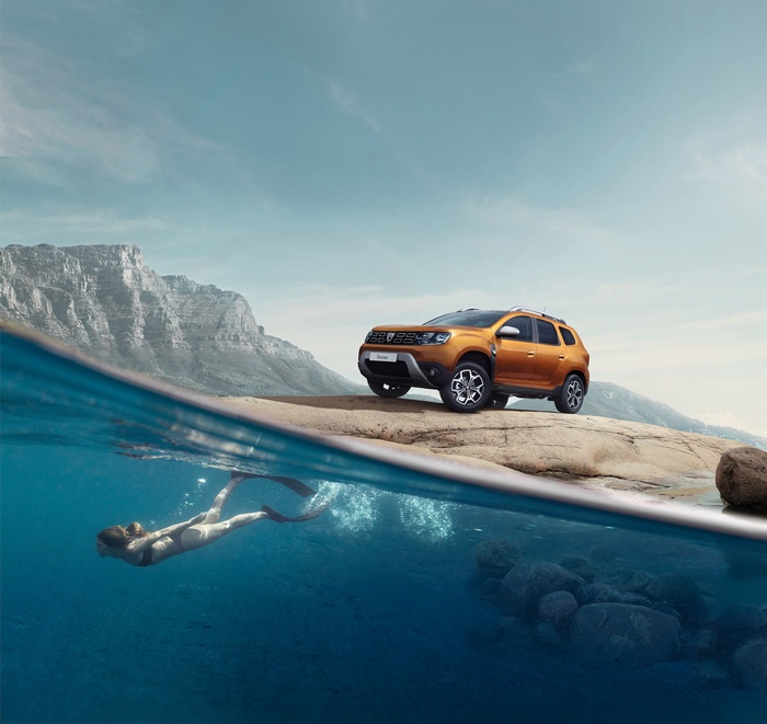 Orange Dacia Duster on rocky shore with swimmer