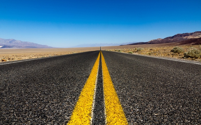 Desert highway with mountains and clear blue sky