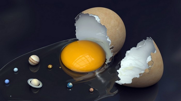 Egg yolk with planets and broken eggshell