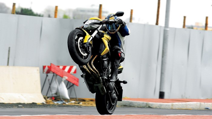 Motorcyclist performing a wheelie on a yellow Honda CB1000R