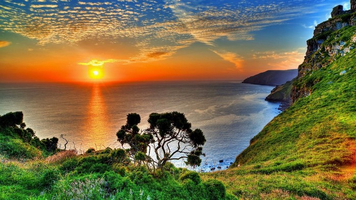 Sunset over the ocean with green cliffs
