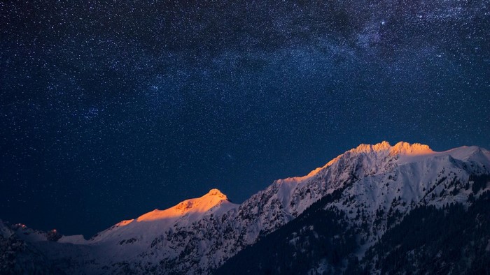 Snowy mountains under a starry night sky