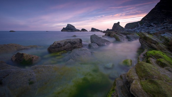 Rocky coastline with purple sky and ocean