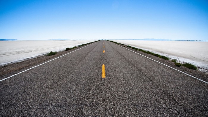Endless road stretching to the horizon under a clear blue sky