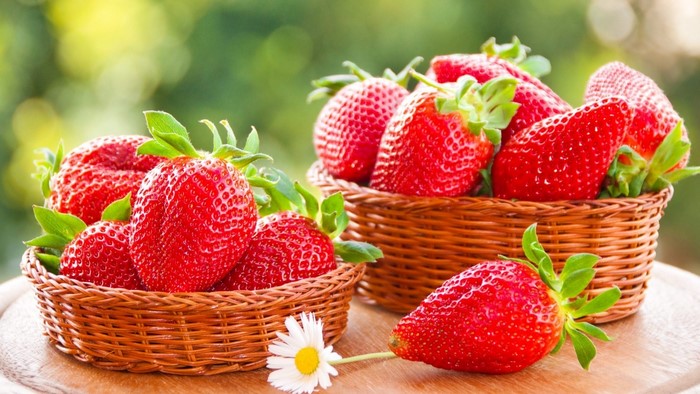 Two baskets of fresh strawberries with a daisy