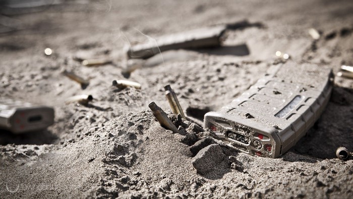 Military rifle magazines and casings in sand