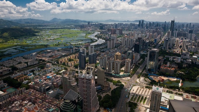 Aerial view of a modern city with a river and mountains