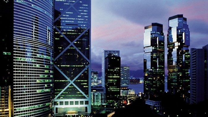Skyscrapers illuminated at dusk with a harbor view