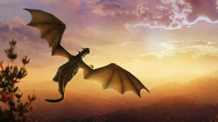 Dragon flying over mountains at sunset