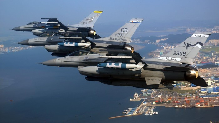 Four F-16 Fighting Falcons fly over a coastal city