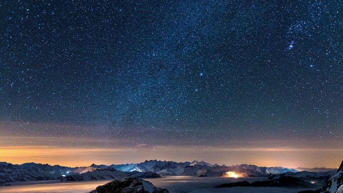 Starry night sky over snow-capped mountains