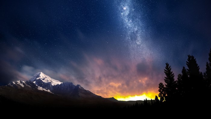 Milky Way over snow-capped mountains and pine forest