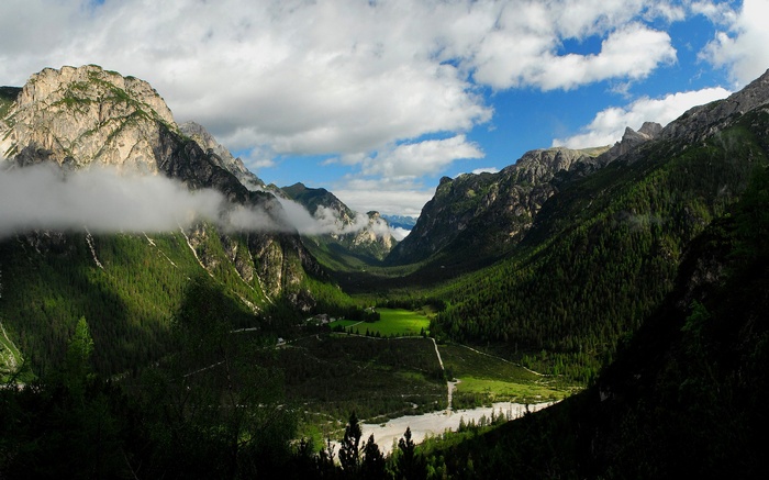 Mountain valley with green forests and clouds