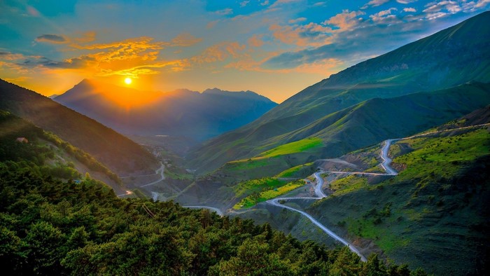 Mountain valley with winding road at sunrise