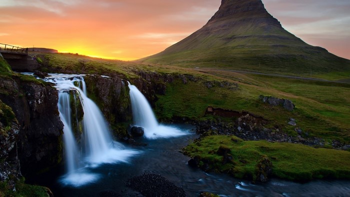 Waterfall near a mountain at sunset