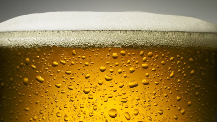 Close-up of a glass of golden beer with foam and condensation