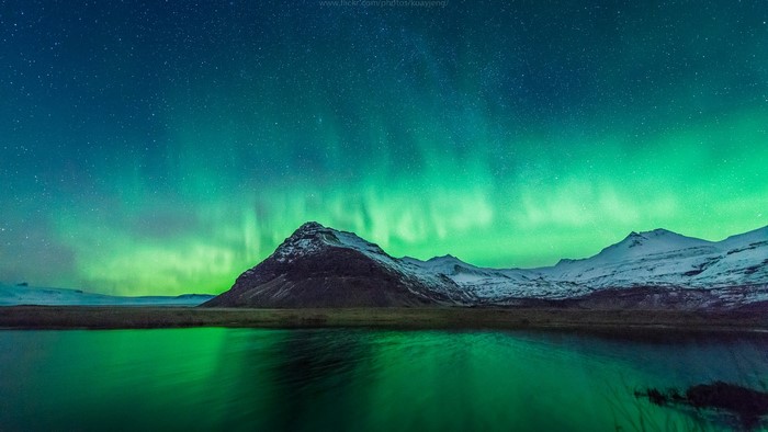 Northern Lights over Snowy Mountains and Lake