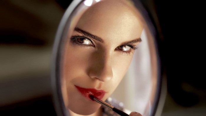 Emma Watson applying red lipstick in a mirror