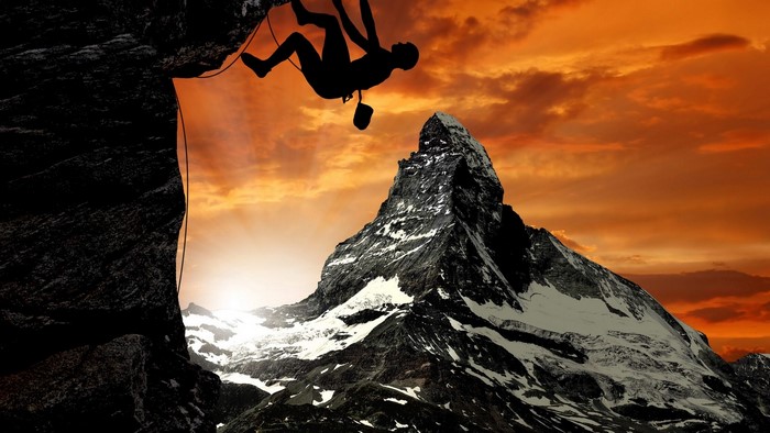 Silhouette of a climber against a mountain and sunset