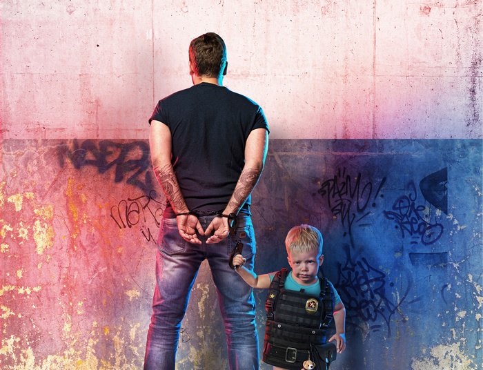 Man in handcuffs with a child in tactical vest
