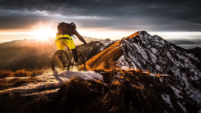 Mountain biker riding on a snowy mountain at sunset