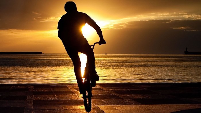 Silhouette of a person on a BMX bike at sunset