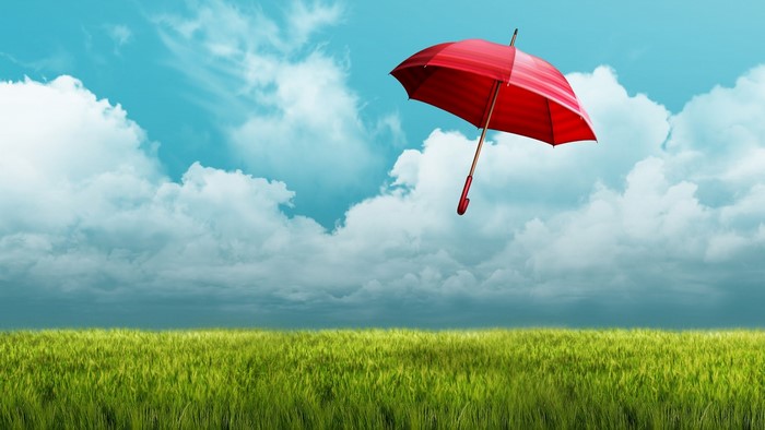 Red umbrella floating over a green field