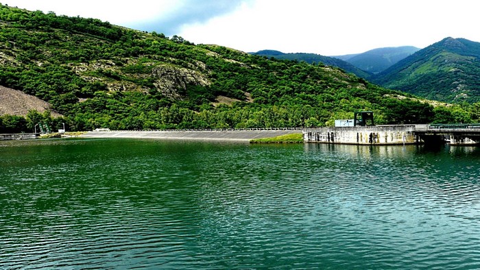 Dam and reservoir surrounded by green mountains