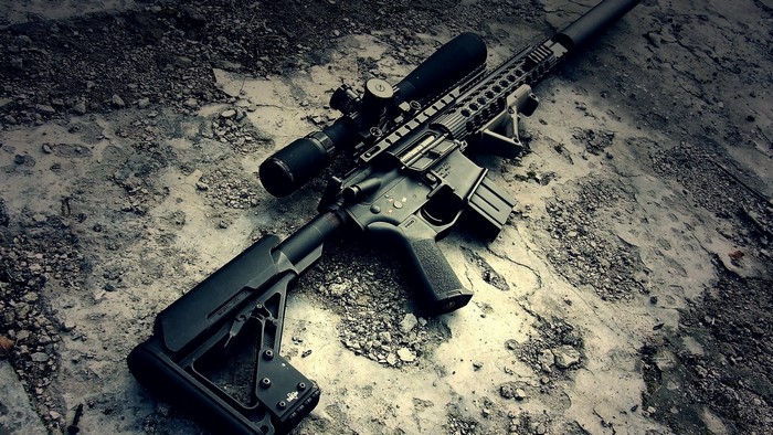 Assault rifle with scope on concrete