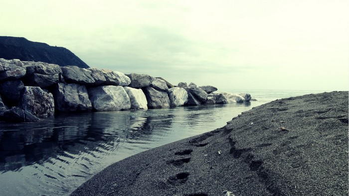 Rocky breakwater and black sand beach